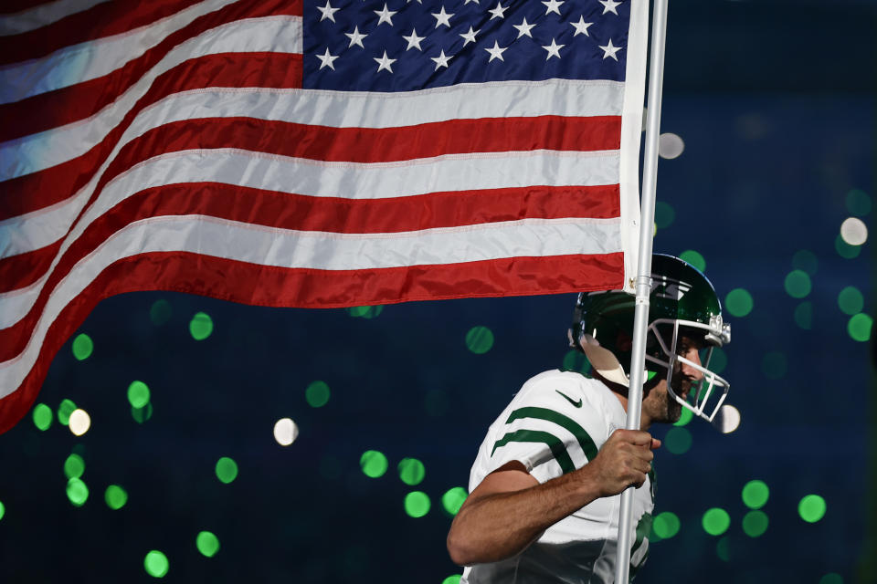 New York Jets quarterback Aaron Rodgers (8) carries an American flag onto the field before playing against the Buffalo Bills in an NFL football game, Monday, Sept. 11, 2023, in East Rutherford, N.J. (AP Photo/Adam Hunger)