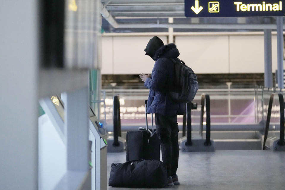 A traveler checks his phone at the O'Hare International Airport in Chicago, Sunday, Jan. 14, 2024. Over 70 flights were cancelled at Chicago airports Sunday. (AP Photo/Nam Y. Huh)