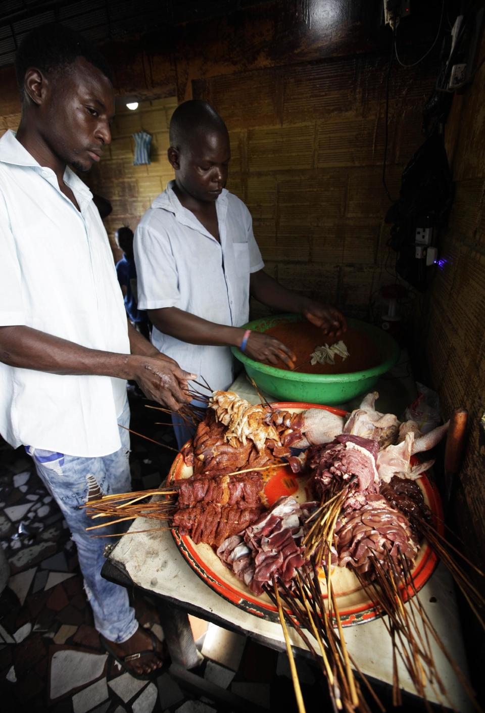 In this photo taken on Saturday, Oct. 20, 2012, men prepare meat to make suya in Lagos, Nigeria. As night falls across Nigeria, men fan the flames of charcoal grills by candlelight or under naked light bulbs, the smoke rising in the air with the smell of spices and cooking meat. Despite the sometimes intense diversity of faith and ethnicity in this nation of 160 million people, that thinly sliced meat called suya, is eaten everywhere. (AP Photo/Sunday Alamba)