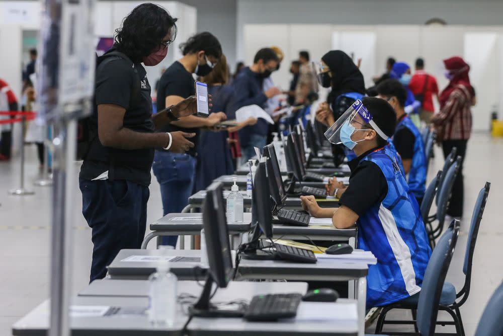 Members of the public register their personal details before receiving the AstraZeneca Covid-19 jab at Universiti Malaya, Kuala Lumpur May 5, 2021. — Picture by Yusof Mat Isa