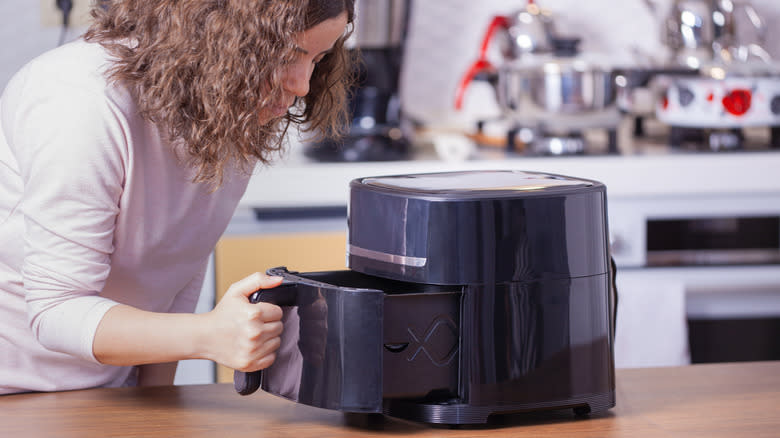 woman looking into air fryer basket