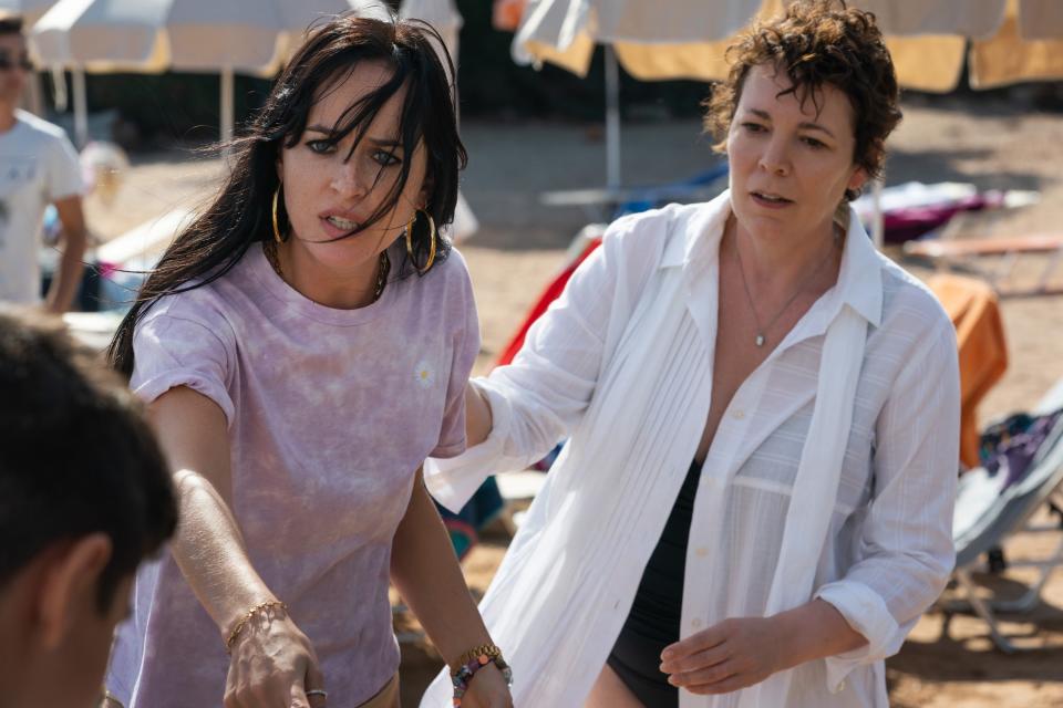 Dakota Johnson and Olivia Colman stand on a beach