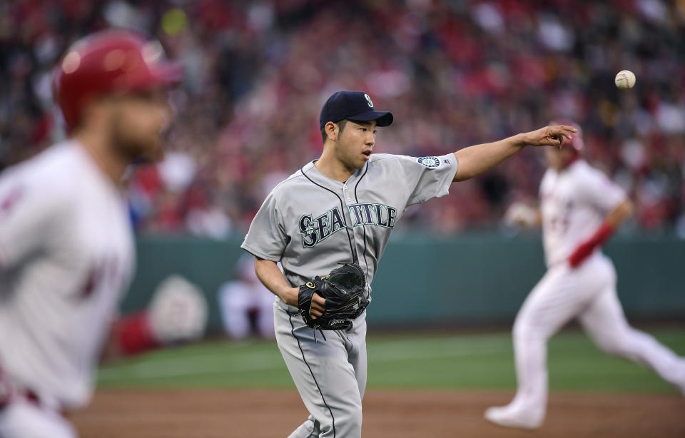 Seattle Mariners starting pitcher Yusei Kikuchi, of Japan, center, throws out Los Angeles Angels' Jonathan Lucroy, left, at first as Mike Trout runs to third during the first inning of a baseball game Saturday, April 20, 2019, in Anaheim, Calif. (AP Photo/Mark J. Terrill)