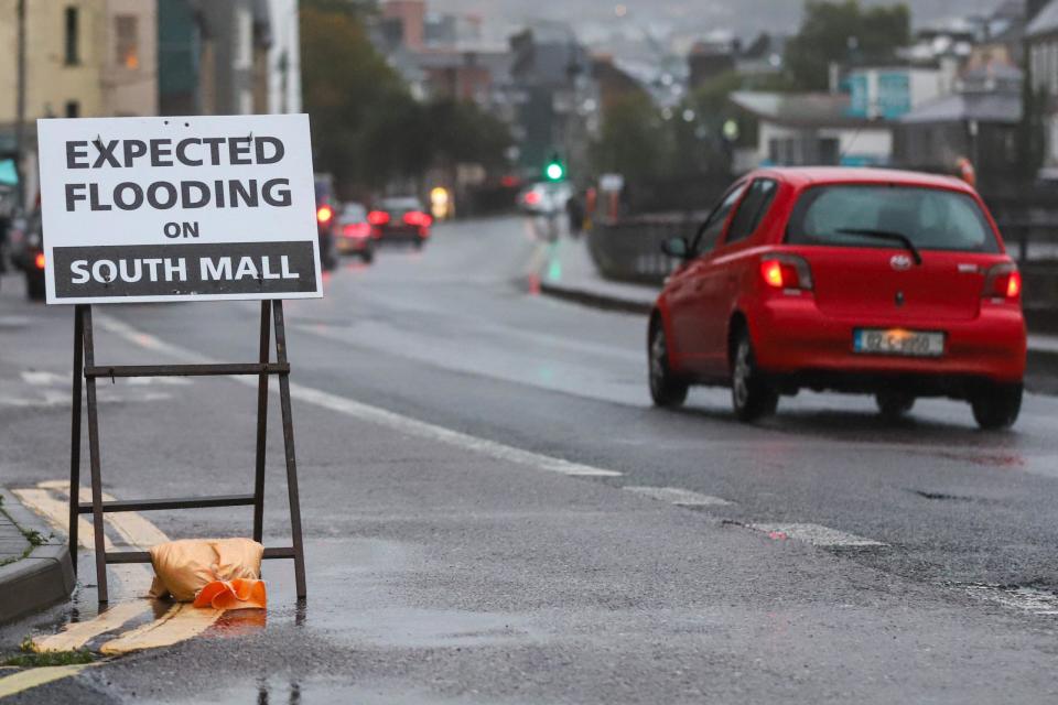 Cars drive by a flood warning sign on George's Quay in Cork city centre on Thursday evening at high tide (PA)