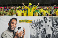 Aficionados de Brasil alientan a la selección detrás de un cartel con imágenes de Pelé, el lunes 5 de diciembre de 2022, antes de un partido del Mundial ante Corea del Sur en Al Rayán, Qatar (AP Foto/Martin Meissner)