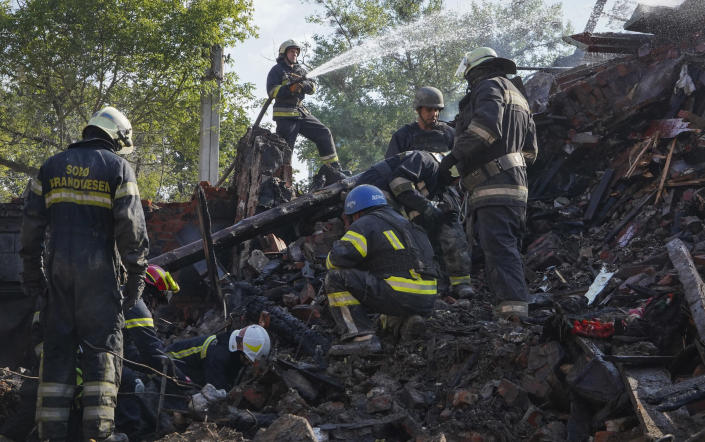 Firefighters dig through the rubble of a building destroyed during a missile strike in Kharkiv, Ukraine, Thursday, Aug. 18, 2022. (AP Photo/Andrii Marienko)