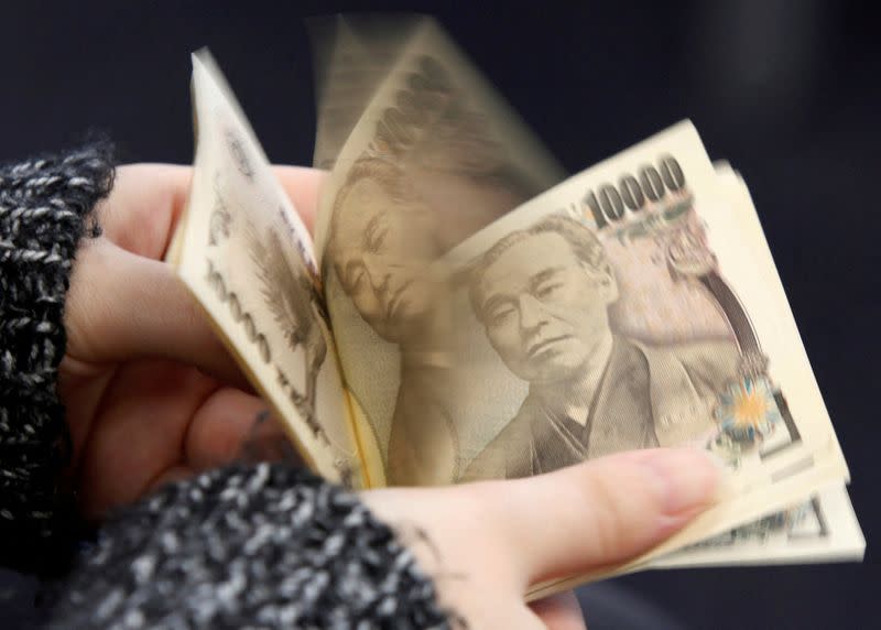 FILE PHOTO: A woman counts Japanese 10,000 yen notes in Tokyo, in this picture illustration