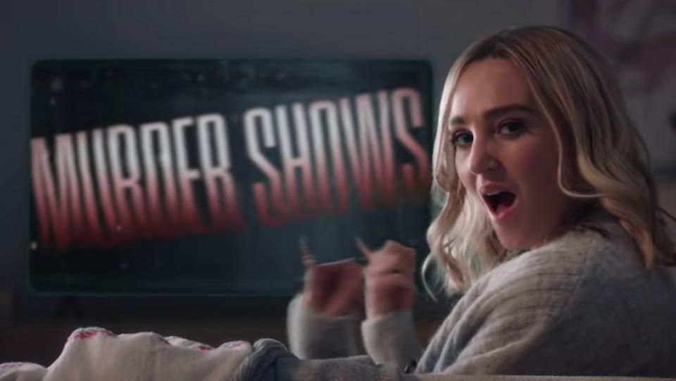 SNL's Chloe Fineman points at her TV screen that says "Murder Shows."