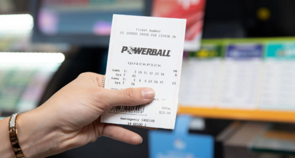 A person holds up a Powerball ticket. The search is on for a second Queensland winner of $50 million.