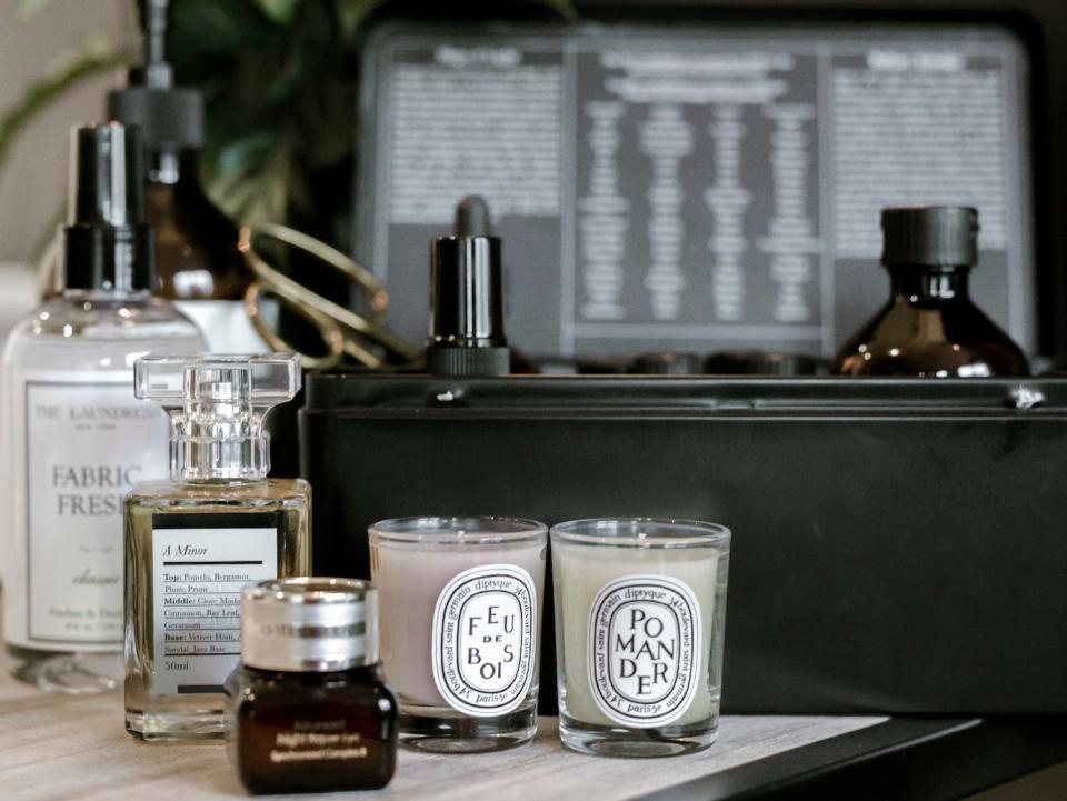 Diptyque candles and perfume on a counter.