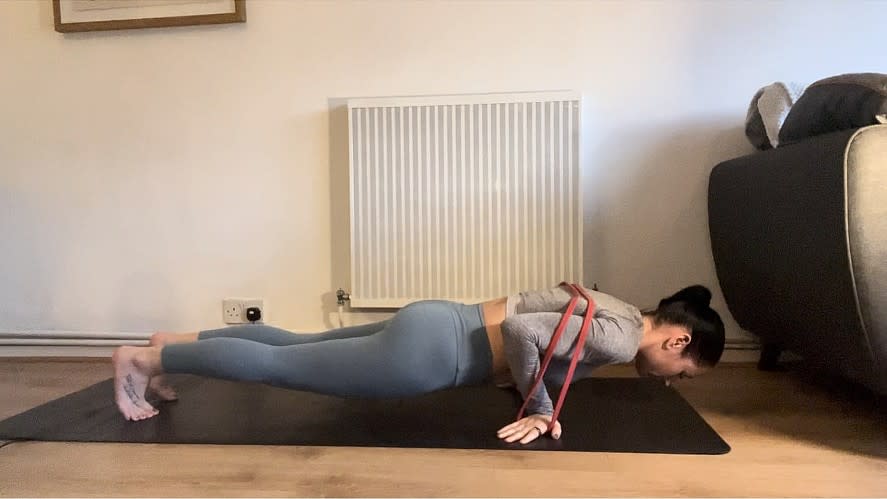 Writer Sam performing a reverse planche push-up with fingers pointed backwards and chest close to the mat