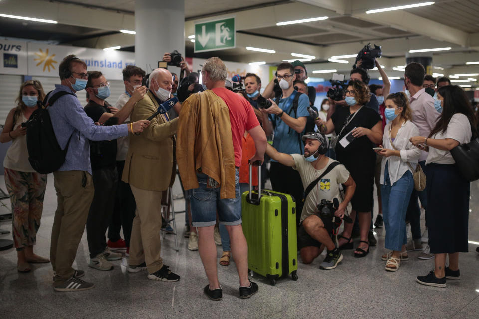 A TUI X3 2312 Duesseldorf-Mallorca flight passenger talks to the press at Son Sant Joan airport in Palma de Mallorca, Spain, Monday, June 15, 2020. Whether its German holidaymakers basking in Spain's sunshine or Parisians renewing their love affair with their city, Monday's border openings and further scrapping of restrictions offered Europeans a taste of pre-coronavirus life that they may have taken for granted. (AP Photo/Joan Mateu)