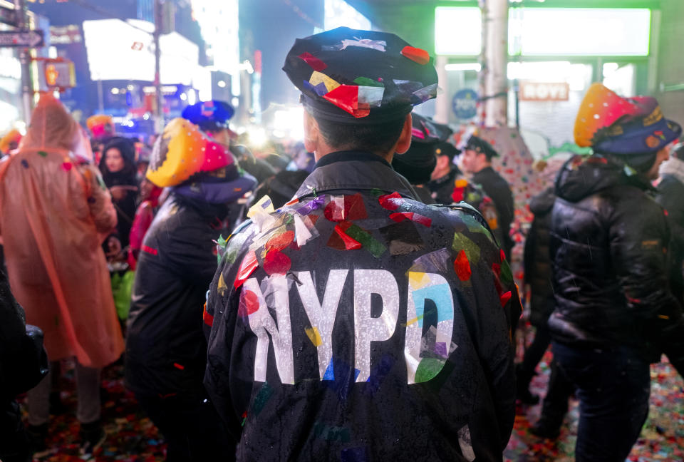 A New York City police officer is covered with confetti in Times Square