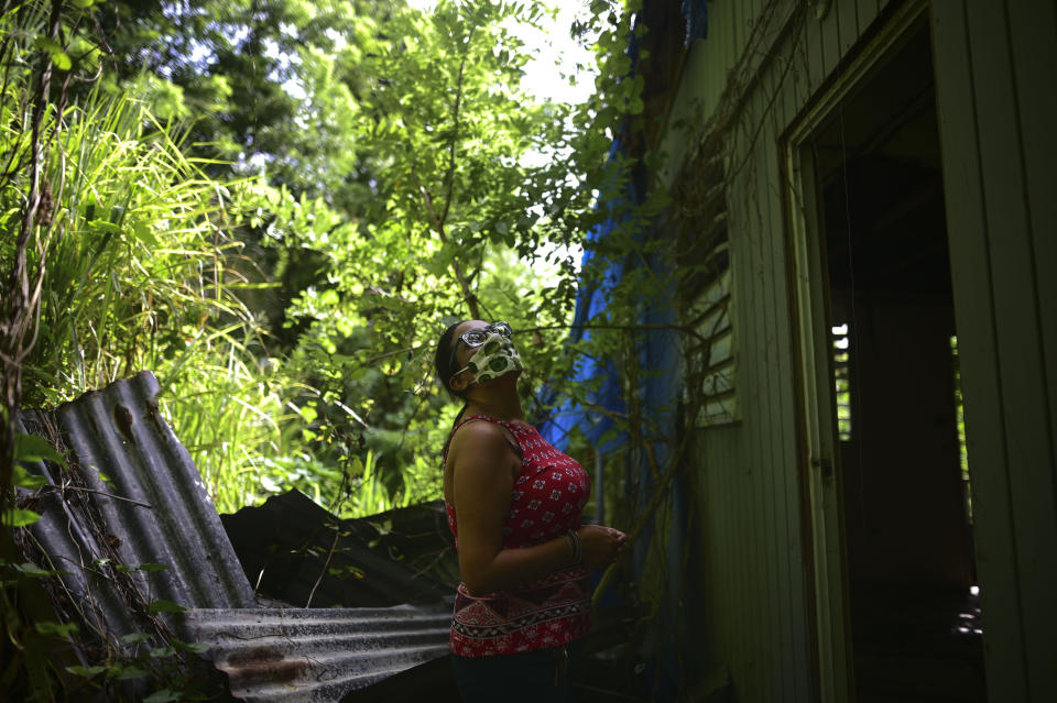 Marian Colon, a single mother of two sons, inspects her hurricane-damaged house in Guaynabo, Puerto Rico, Tuesday, July 14, 2020. Hurricane Maria tore off her roof and caused a nearby landslide that put her home in jeopardy, and nothing has been fixed or repaired for nearly three years. During that time, she has bounced from home to home thanks to the generosity of relatives, but she is anxious to settle down. (AP Photo/Carlos Giusti)