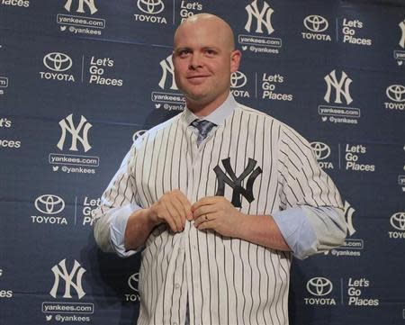 Dec 5, 2013; Bronx, NY, USA; New York Yankees newly signed catcher Brian McCann puts on his new jersey during a press conference at Yankee Stadium. William Perlman-The Star-Ledger