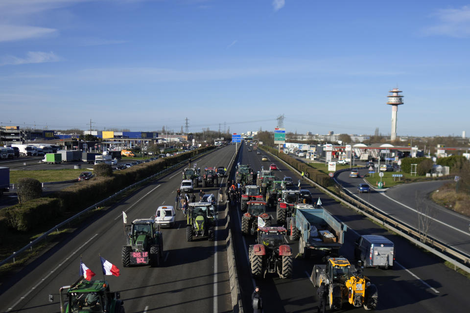 Tractors are parked on a highway in Villabe, south of Paris, Friday, Jan. 26, 2024 in Paris. Protesting farmers shut down long stretches of some of France's major motorways on Friday, using their tractors to block and slow traffic and squeeze the government ever more tightly to cede to their demands that growing and rearing food should be made easier and more lucrative. (AP Photo/Thibault Camus)