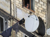 A man smokes and looks through the window of his apartment in Stepanakert, the separatist region of Nagorno-Karabakh, Friday, Oct. 23, 2020. Heavy fighting over Nagorno-Karabakh is continuing with Armenia and Azerbaijan trading blame for new attacks. Two Russia-brokered cease-fires collapsed instantly after taking effect, and the warring parties have continued to exchange blows with heavy artillery, rockets and drones. (AP Photo)