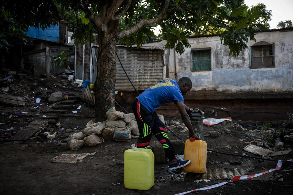 Une photo prise le 23 mai 2023 à Koungou où un habitant rempli des jerricanes d’eau potable près du bidonville du quartier « Talus 2 ».