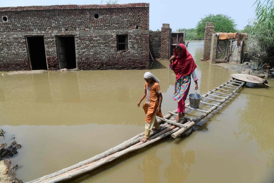 Two women cross a temporary bamboo path near their flooded house in Shikarpur on Monday (Asif Hasan/AFP/Getty)