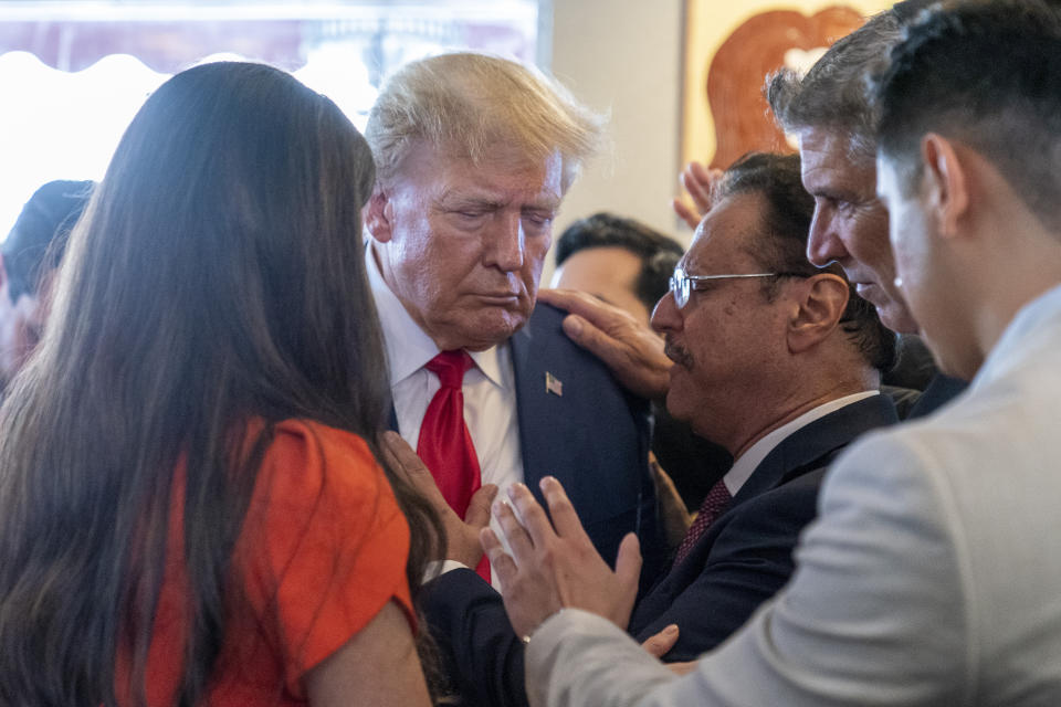 Former President Donald Trump prays with pastor Mario Bramnick, third from right, and others at Versailles restaurant on Tuesday, June 13, 2023, in Miami. Trump appeared in federal court Tuesday on dozens of felony charges accusing him of illegally hoarding classified documents and thwarting the Justice Department's efforts to get the records back. (AP Photo/Alex Brandon)