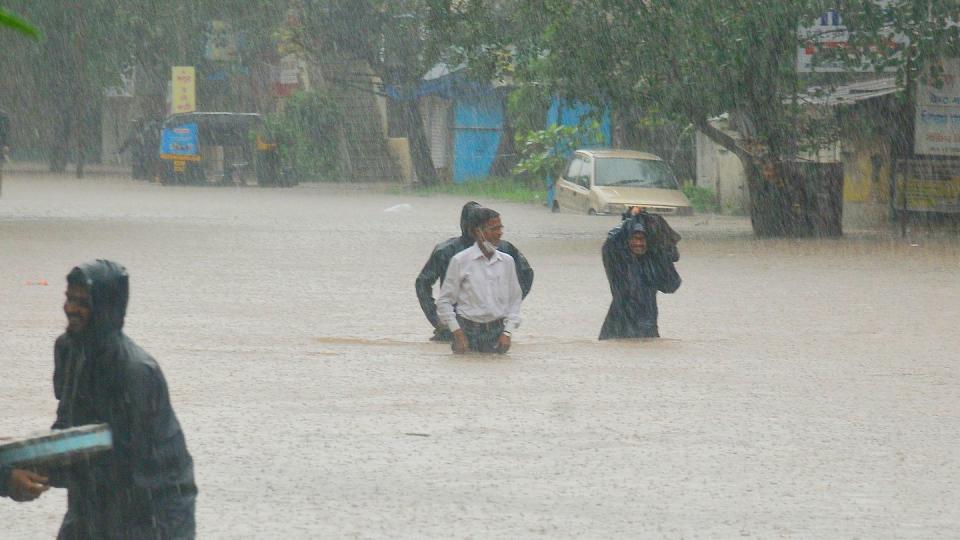 Menschen waten in Kolhapur durch das Hochwasser.