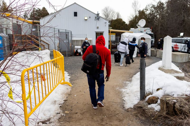 People wait for transport to cross into Canada at Roxham Road, in Plattsburgh