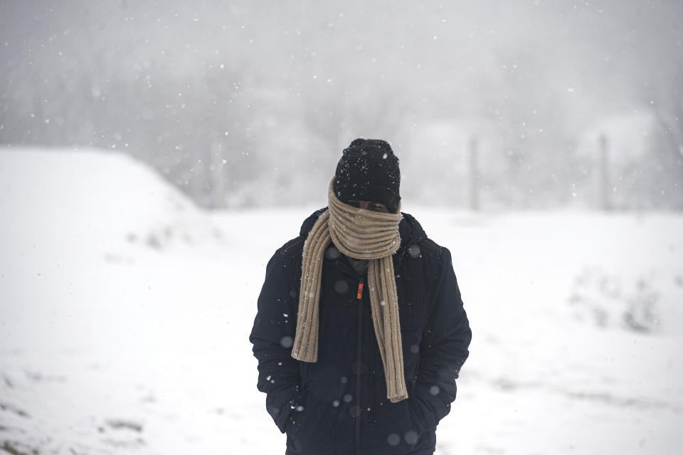 A migrant walks during snowfall at the Lipa camp, outside Bihac, Bosnia, Friday, Jan. 8, 2021. A fresh spate of snowy and very cold winter weather on has brought more misery for hundreds of migrants who have been stuck for days in a burnt out camp in northwest Bosnia waiting for heating and other facilities. (AP Photo/Kemal Softic)