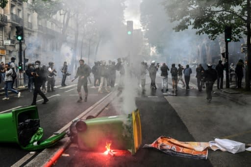 A burning flare next to trash containers during a demonstration in Paris on Tuesday against President Emmanuel Macron's plans to overhaul France's public sector