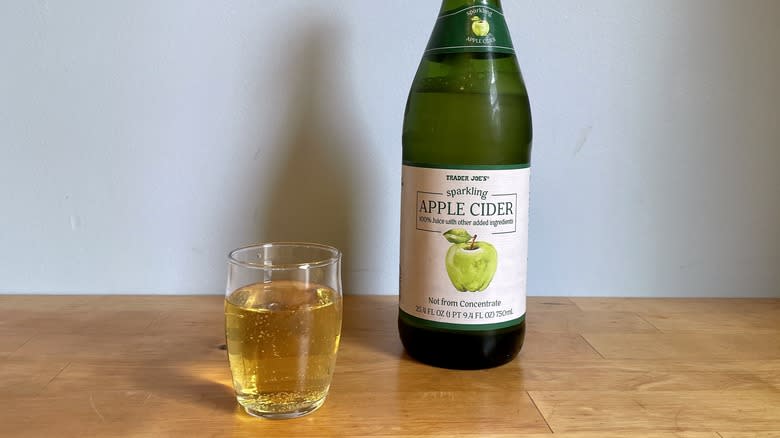 Green bottle of Trader Joe's apple cider with glass of cider