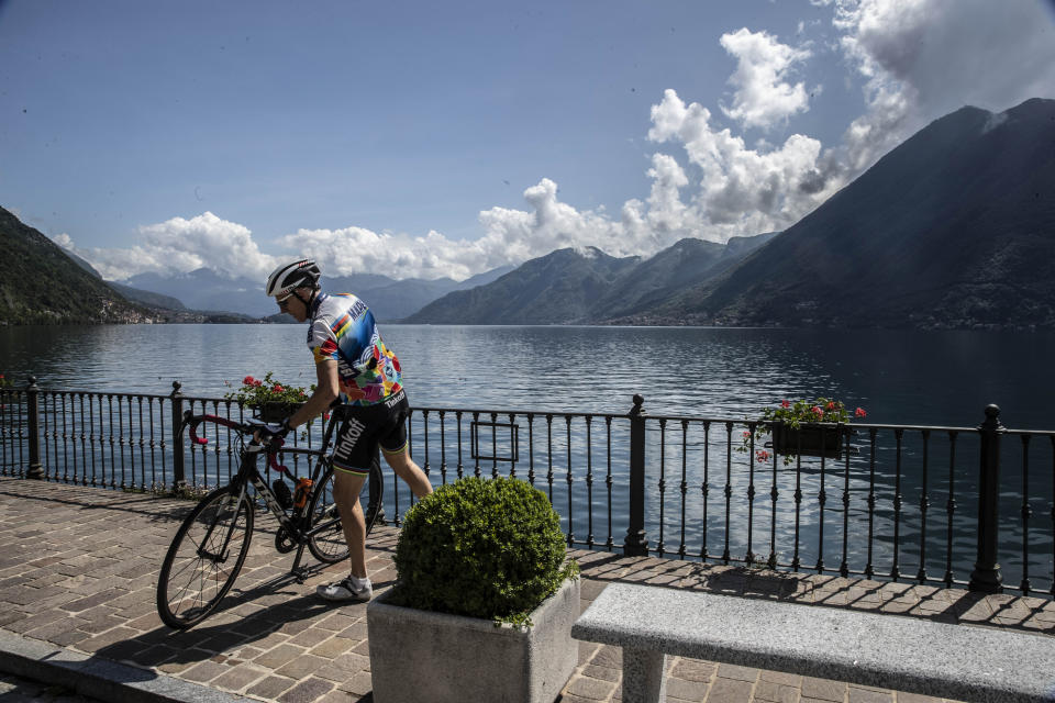 A man gets on his bicycle in Argegno, Lake Como, Italy, Thursday, May 14, 2020. (AP Photo/Luca Bruno)