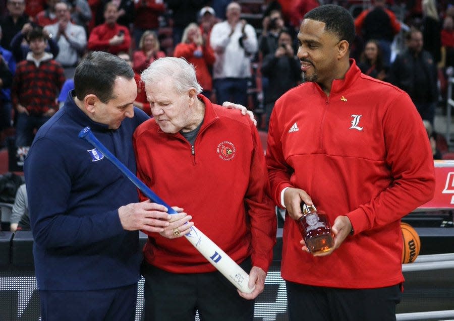 Louisville interim coach Mike Pegues and former coach Denny Crum present Duke coach Mike Krzyzewski with a Louisville Slugger and a bottle of bourbon.