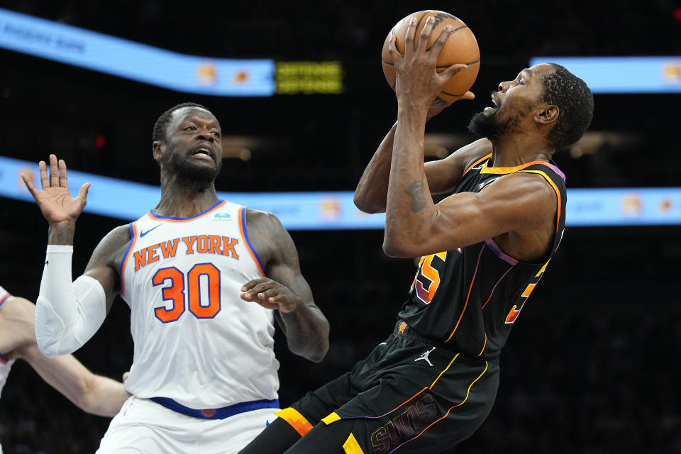 Phoenix Suns forward Kevin Durant drives as New York Knicks forward Julius Randle (30) defends during the first half of an NBA basketball game, Friday, Dec. 15, 2023, in Phoenix. (AP Photo/Matt York)