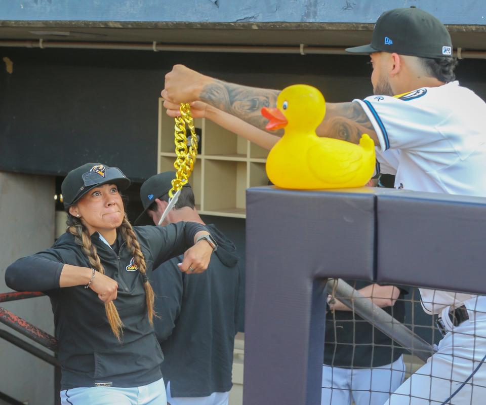 RubberDucks assistant hitting coach Amanda Kamekona flexes as the home run chain is put on the dugout duck before the game against the Erie SeaWolves earlier this week.
