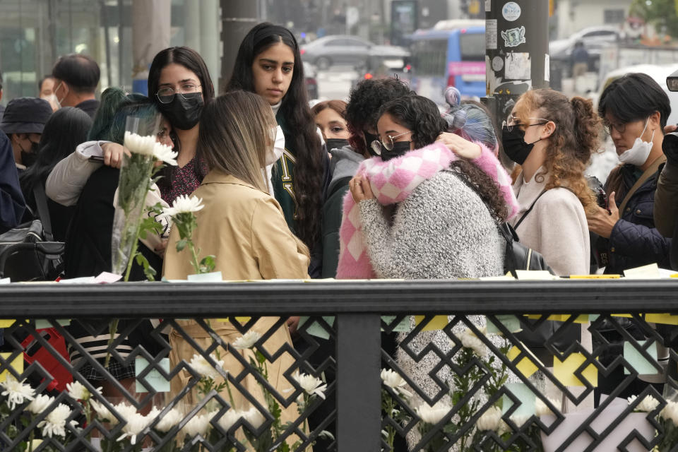 Mourners react as they pay tribute to victims of a deadly accident following Saturday night's Halloween festivities on a street near the scene in Seoul, South Korea, Tuesday, Nov. 1, 2022. South Korean police are investigating what caused a crowd surge that killed more than 150 people during Halloween festivities in Seoul over the weekend. (AP Photo/Ahn Young-joon)