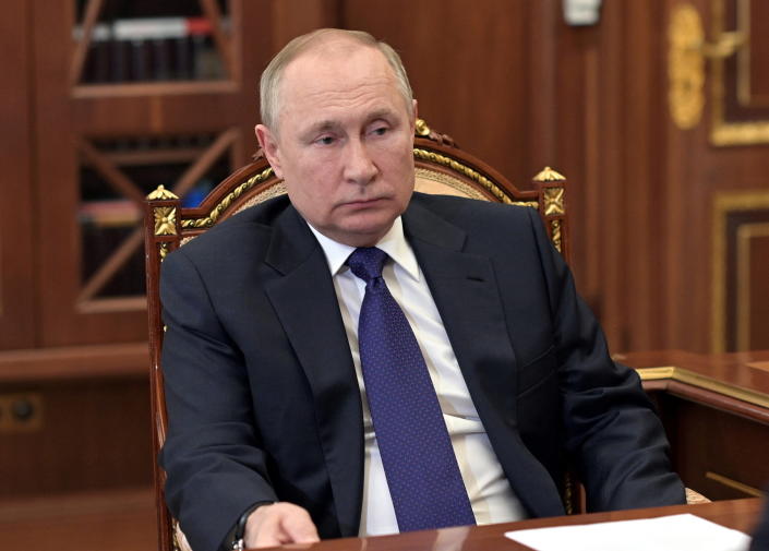 Russian President Vladimir Putin silts in a gilded chair looking glum.