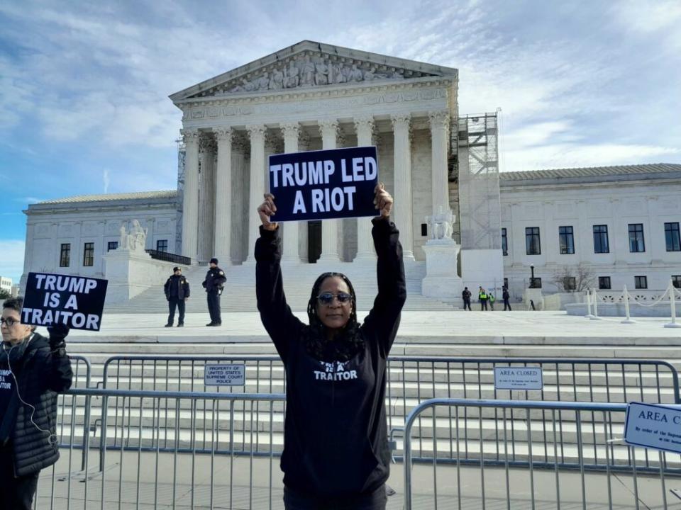 Valarie Walker of New York City holds a sign reading "Trump Led a Riot" in front of the U.S. Supreme Court Thursday, Feb. 8, 2024.