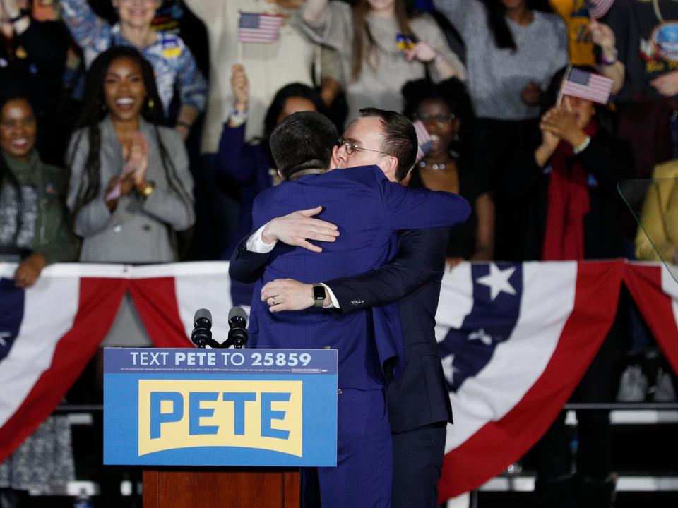 pete and chasten buttigieg hugging on stage at campaign event