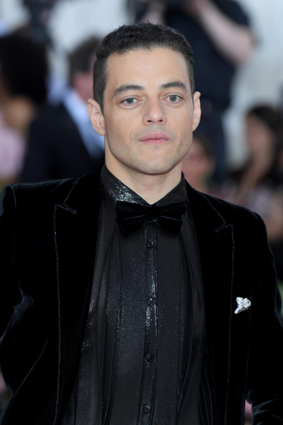 Rami Malek wore Panthère de Cartier brooch, 18k white gold, emeralds, onyx, diamonds and Cartier Tank MC watch, large model, steel, leather. (Photo by Karwai Tang/WireImage )