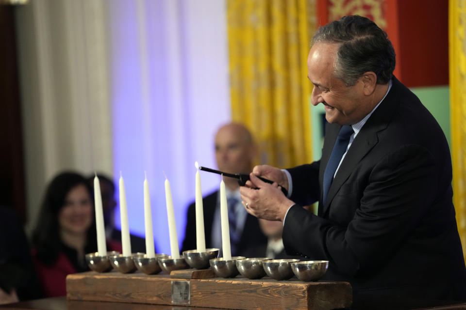 Second gentleman Doug Emhoff lights the Shamash on menorah during a Hanukkah reception with President Joe Biden in the East Room of the White House in Washington, Monday, Dec. 11, 2023. (AP Photo/Jacquelyn Martin, Pool)