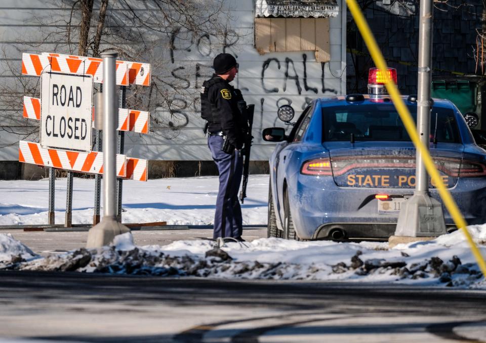 A Michigan state trooper with a long gun stands at the intersection of Pleasant Grove and Jolly roads Saturday, Jan. 8, 2022 during negotiations with an armed man barricaded in his home in the area. Police later found the body of a woman in the home, they said Sunday.