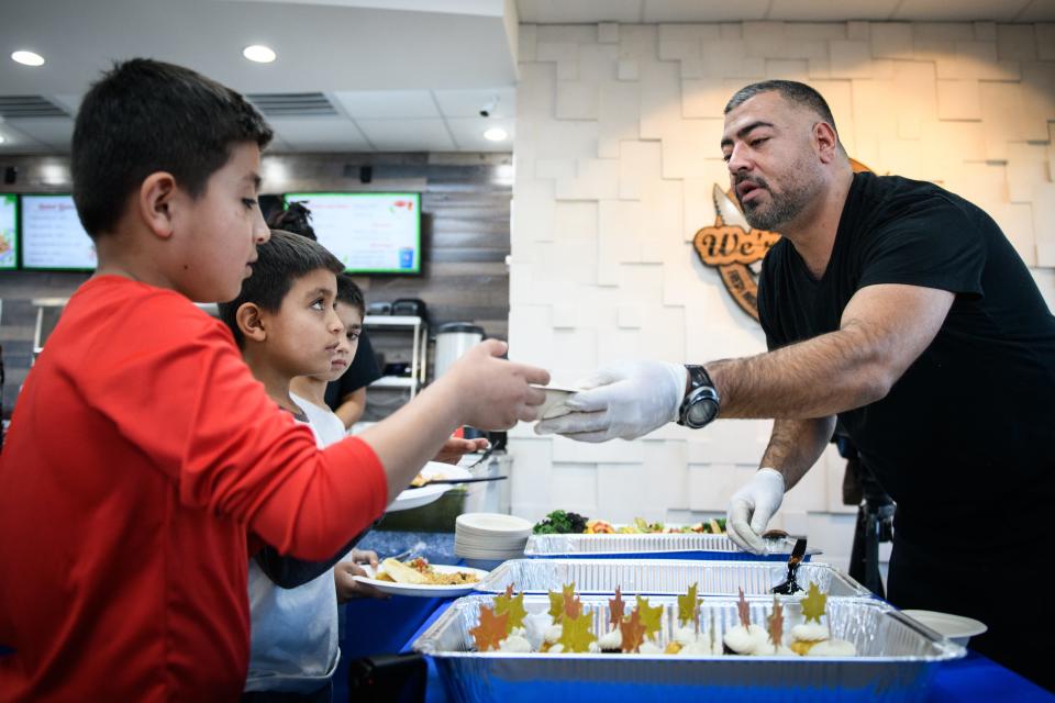 Helal Dur, right, hands a bowl of fruit to Najeebullah Habibi during a meet up of Afghan refugees, veterans and others at Afghan Kabob on Sunday, Nov. 14, 2021.
