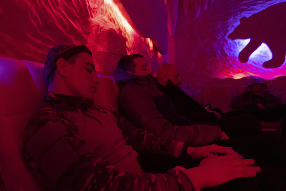 Ukrainian soldier Viktor 'Shahtar' listens to meditation music as he sits with comrades in a low lit room at a rehabilitation center in Kharkiv region, Ukraine, Friday, Dec. 30, 2022. Viktor, who worked as a miner before joining the army, took part in the military operation that pushed Russian occupying forces out of the Kharkiv region. (AP Photo/Vasilisa Stepanenko)