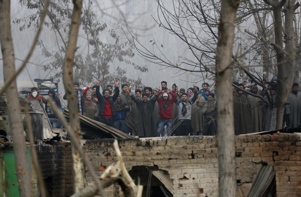 Kashmiri villagers shout pro-freedom slogans next to damaged houses at the site of a gun-battle in Mujagund area some 25 Kilometers (16 miles) from Srinagar, Indian controlled Kashmir, Sunday, Dec. 9, 2018. Indian troops killed three suspected rebels in the outskirts of disputed Kashmir's main city ending nearly 18-hour-long gunbattle, officials said Sunday. (AP Photo/Mukhtar Khan)