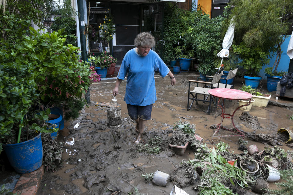 A woman walks through debris following a storm at the village of Politika, on Evia island, northeast of Athens, on Sunday, Aug. 9, 2020. Five people have been found dead and dozens have been trapped in their homes and cars from a storm that has hit the island of Evia, in central Greece, police say. (AP Photo/Yorgos Karahalis)
