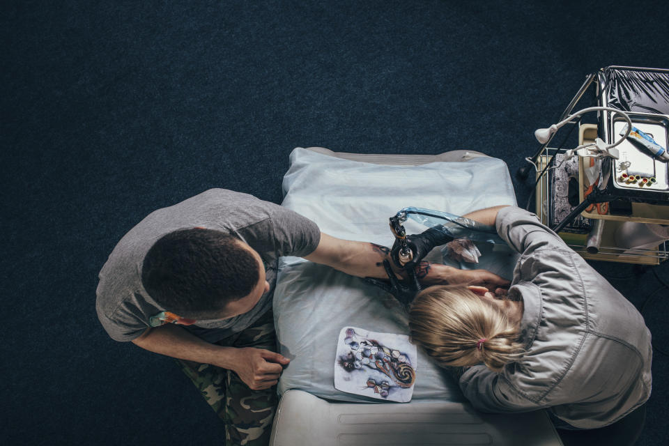 A tattoo artist working on a client