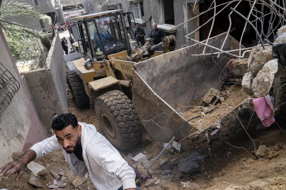 A bulldozer is used to clear a street of debris beside the crater where the home of Ramez al-Masri was destroyed by an air-strike prior to a cease-fire reached after an 11-day war between Gaza's Hamas rulers and Israel, Sunday, May 23, 2021, in Beit Hanoun, the northern Gaza Strip. (AP Photo/John Minchillo)