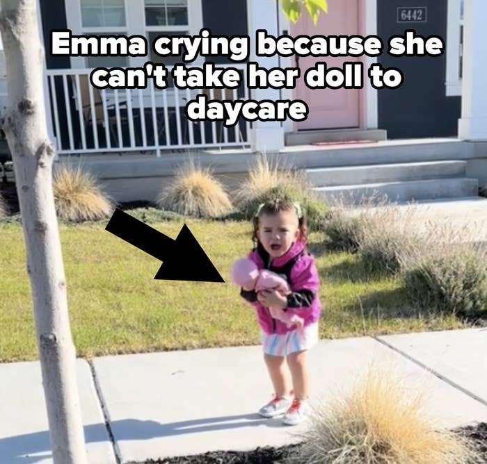 A young girl stands on a sidewalk holding a doll with a house and garden in the background. Text reads: "*** the end though ??"