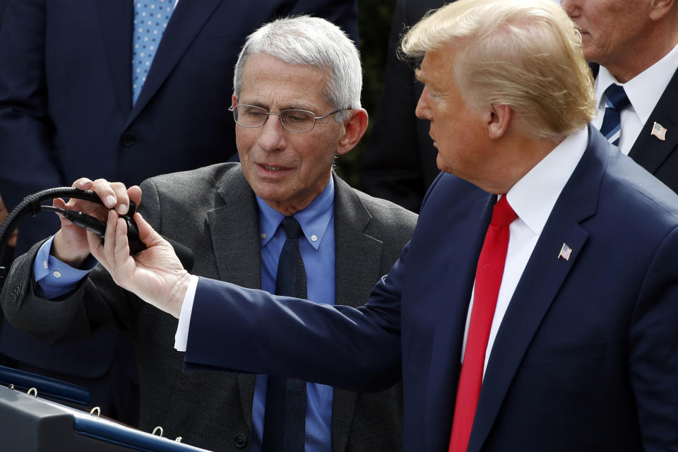 President Donald Trump adjusts the microphone for Dr. Anthony Fauci, director of the National Institute of Allergy and Infectious Diseases, during a news conference about the coronavirus in the Rose Garden at the White House, Friday, March 13, 2020, in Washington. (AP Photo/Alex Brandon)