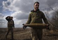 FILE - Ukrainian soldiers carry shells to fire at Russian positions on the front line, near the city of Bakhmut, in Ukraine's Donetsk region, on March 25, 2024. The outgunned and outnumbered Ukrainian troops are struggling to halt Russian advances as a new U.S. aid package is stuck in Congress. (AP Photo/Efrem Lukatsky, File)