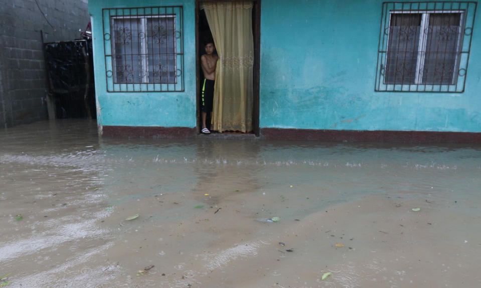 A resident stands in the doorway of his home as it continues to rain in San Manuel, Honduras, Wednesday, Nov. 4, 2020. Eta weakened from the Category 4 hurricane to a tropical storm after lashing the Caribbean coast for much of Tuesday, its floodwaters isolating already remote communities and setting off deadly landslides. (AP Photo/Delmer Martinez)